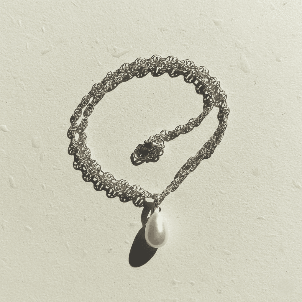 Silver chain necklace with pearl pendant on plain white background